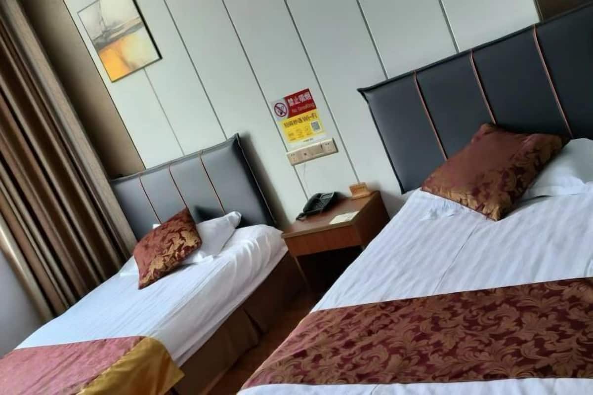 Two beds with headboards, a nightstand, a wall-mounted telephone, and a safety sign.