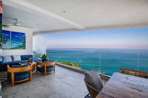 Un balcon avec vue sur la mer, aménagé avec un canapé, des chaises et une table.