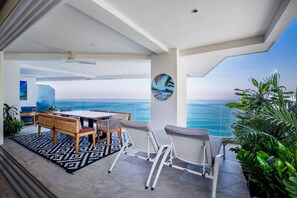 En balkon med havudsigt, et spisebord med stole og et billede på væggen.