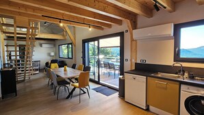 Una cocina moderna con lavavajillas, un comedor con mesa y sillas, una escalera y vistas al exterior.