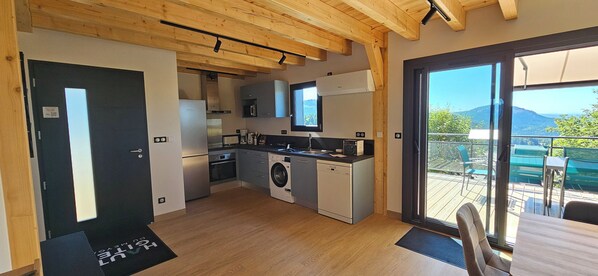 A modern kitchen with built-in appliances, a dining area with a view, and a sliding glass door to an outdoor deck.