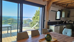 Una cocina moderna con vistas a las montañas, un comedor con una mesa de madera y un amplio ventanal corredera.