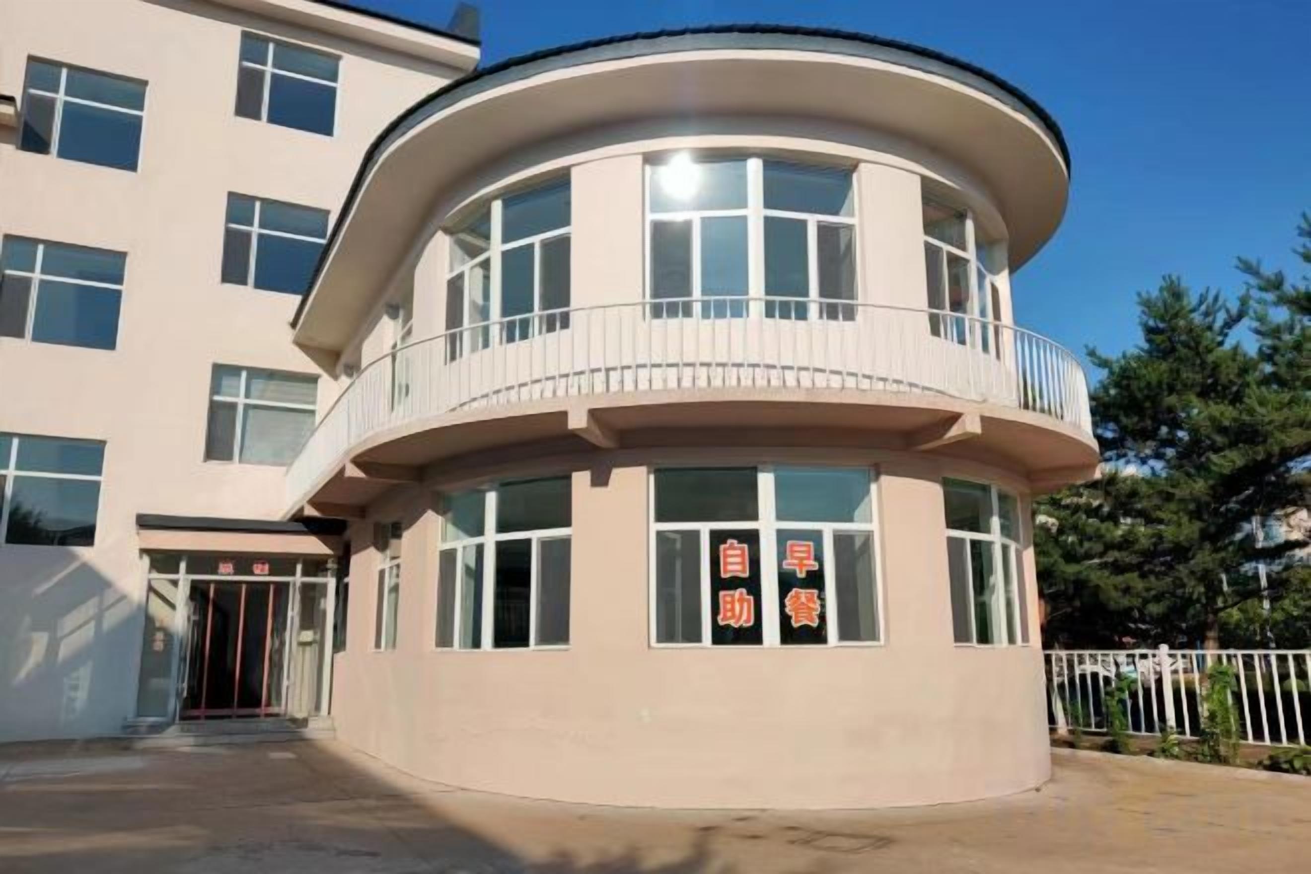 A multi-story building with a curved facade, a balcony on the upper level, and a sign with Chinese characters.