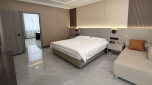 A modern hotel room with a large bed, bedside tables, a wardrobe, and a bathroom visible through a door. - Dongguan Hotel (Tumen)