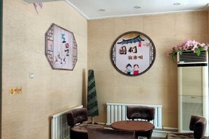A room with a round table and chairs, a radiator, and decorative wall art. - Dongguan Hotel (Tumen)