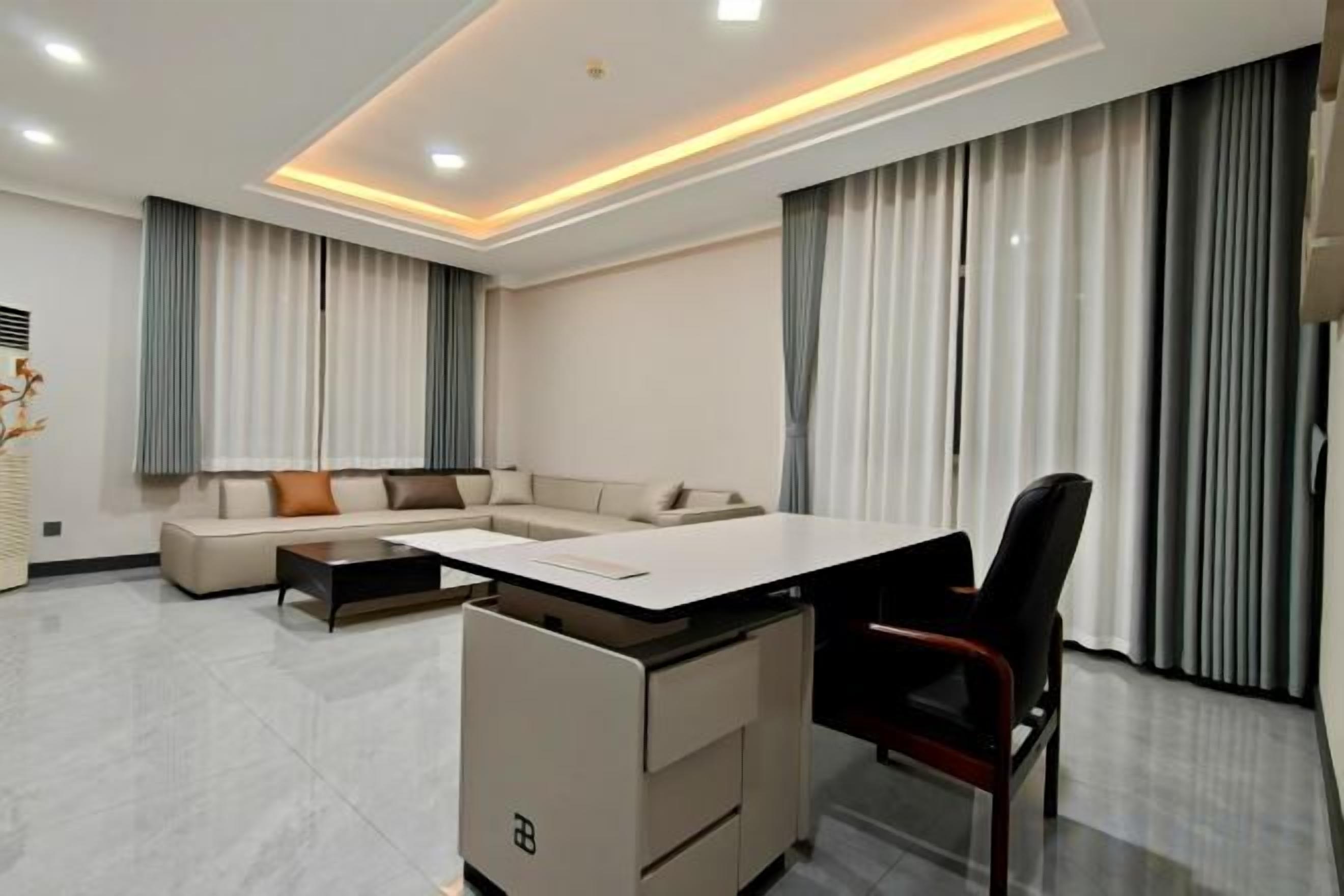 A modern living room with a sectional sofa, a dining table, and a black office chair.