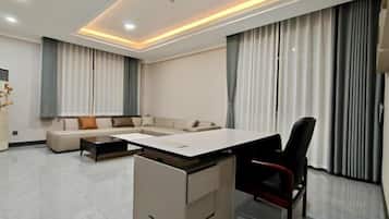 A modern living room with a sectional sofa, a dining table, and a black office chair.