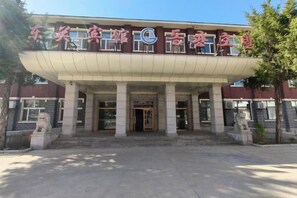 A building with a large entrance, columns, and a sign with Chinese characters. - Dongguan Hotel (Tumen)