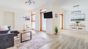 A modern living room with a sofa, coffee table, and a TV mounted on the wall. - P&O Apartments Arkadia 1 (Warsaw)