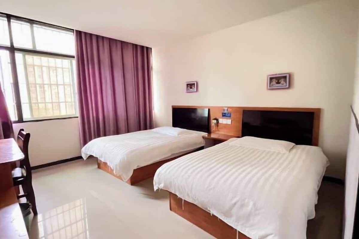 Quarto de hotel com duas camas, uma escrivaninha e uma cadeira.