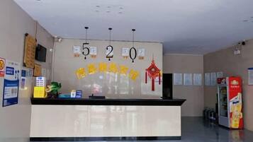 A reception desk with a digital display, a vending machine, and a wall with numbered signs.