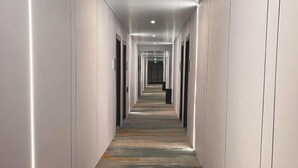 A long, narrow hallway with a patterned carpet and recessed lighting.