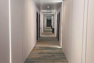 Un pasillo largo y estrecho con alfombra estampada e iluminación empotrada.