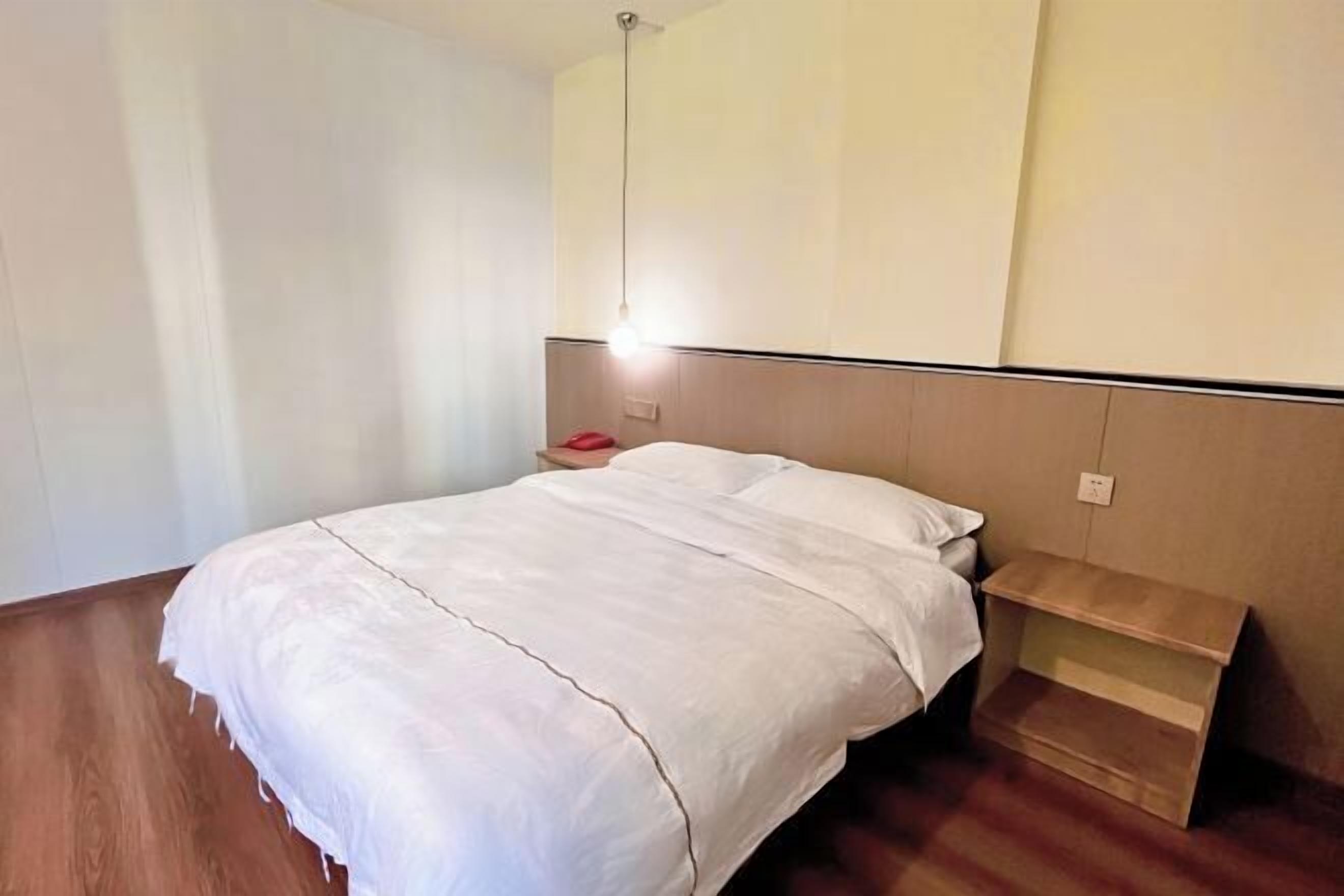 A bedroom with a bed, a bedside table, and a nightstand.