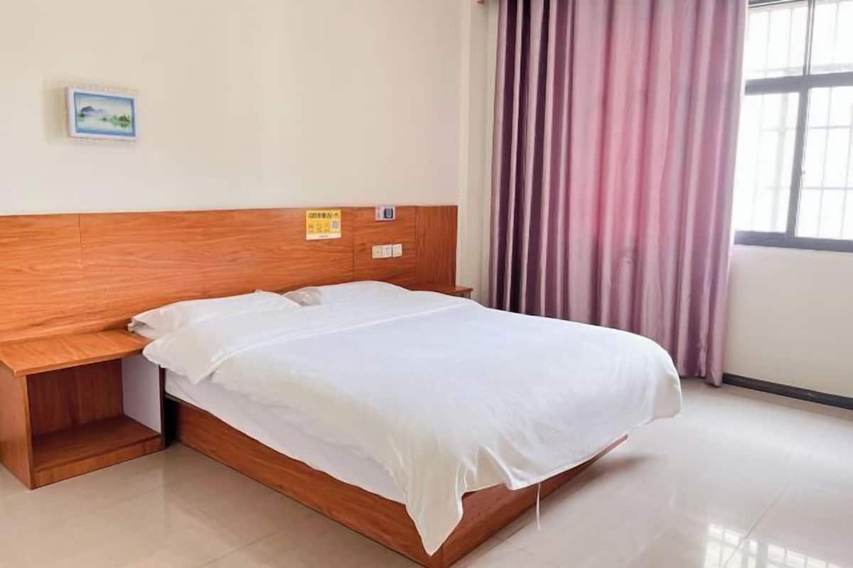 Uma cama bem arrumada com cabeceira de madeira, uma pequena mesa de cabeceira e um quadro na parede.
