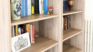 A bookshelf with various books, a ceramic vase, and a small figurine. - Ponchielli 8 Vintage Flat (Florence)