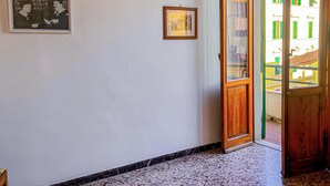 A room with a tiled floor, a wooden door, and two framed pictures on the wall. - Ponchielli 8 Vintage Flat (Florence)