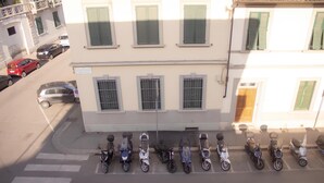 A row of parked scooters in front of a building with multiple windows and a crosswalk. - Ponchielli 8 Vintage Flat (Florence)