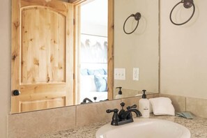 A bathroom with a wooden door, a sink with a black faucet, a hand soap dispenser, and a towel on the counter.