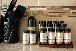 A kitchen counter with various spices and a bottle of olive oil.