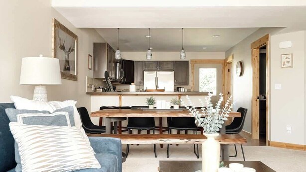 Una sala de estar moderna con un sofá azul, una mesa de centro de madera y una zona de comedor con una mesa y sillas de madera.