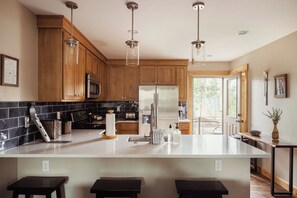 Una cocina moderna con armarios de madera, electrodomésticos de acero inoxidable y una isla grande con taburetes de bar.