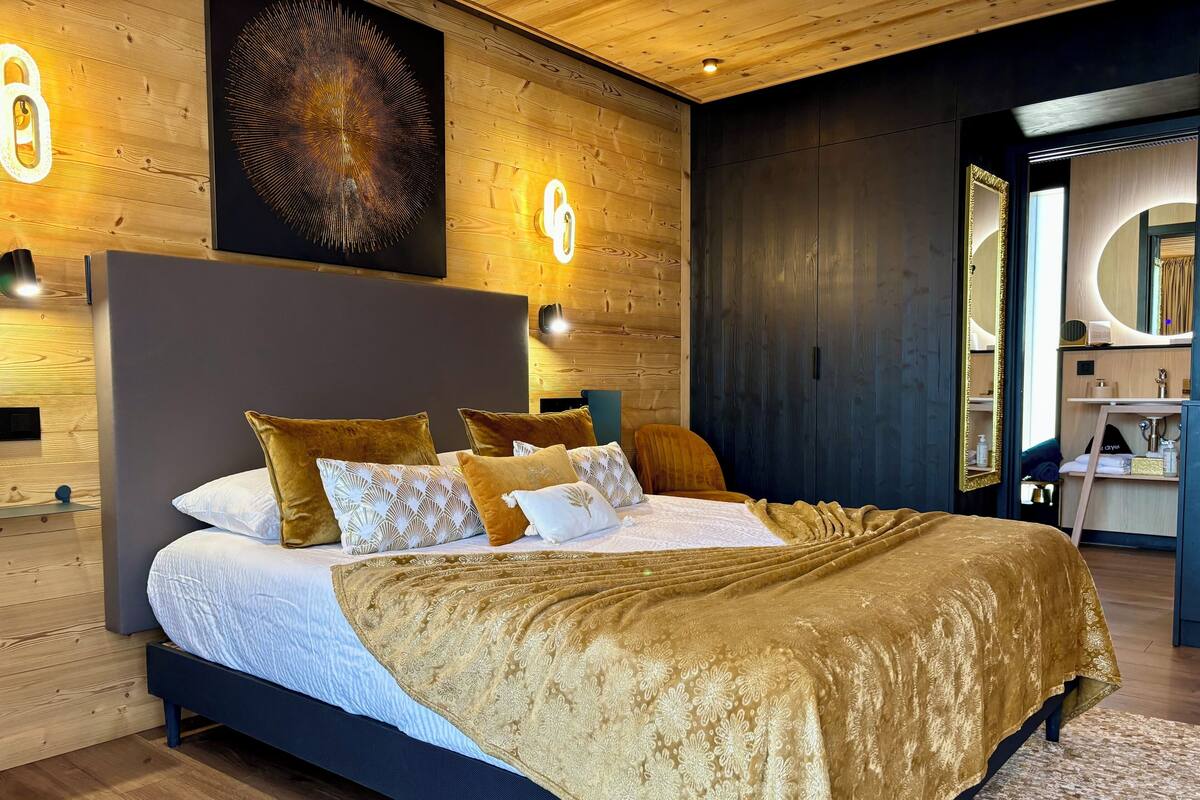 A modern bedroom with a large bed, wooden walls, and a built-in wardrobe.