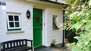 A white cottage with a green door, a bench, and potted plants. - Y Cwtch, Newport - One Bedroom Cottage, Sleeps 2 (Newport)