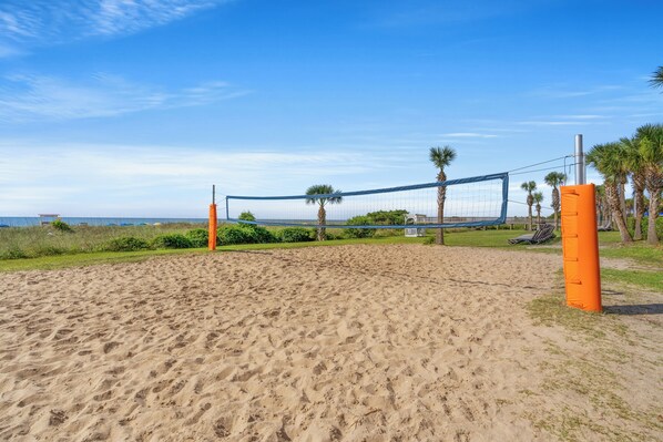 A beach volleyball court with a net, sand, and palm trees. - 2 BR Dunes Village 255 - Waterpark Onsite - Great for Families (Myrtle Beach)
