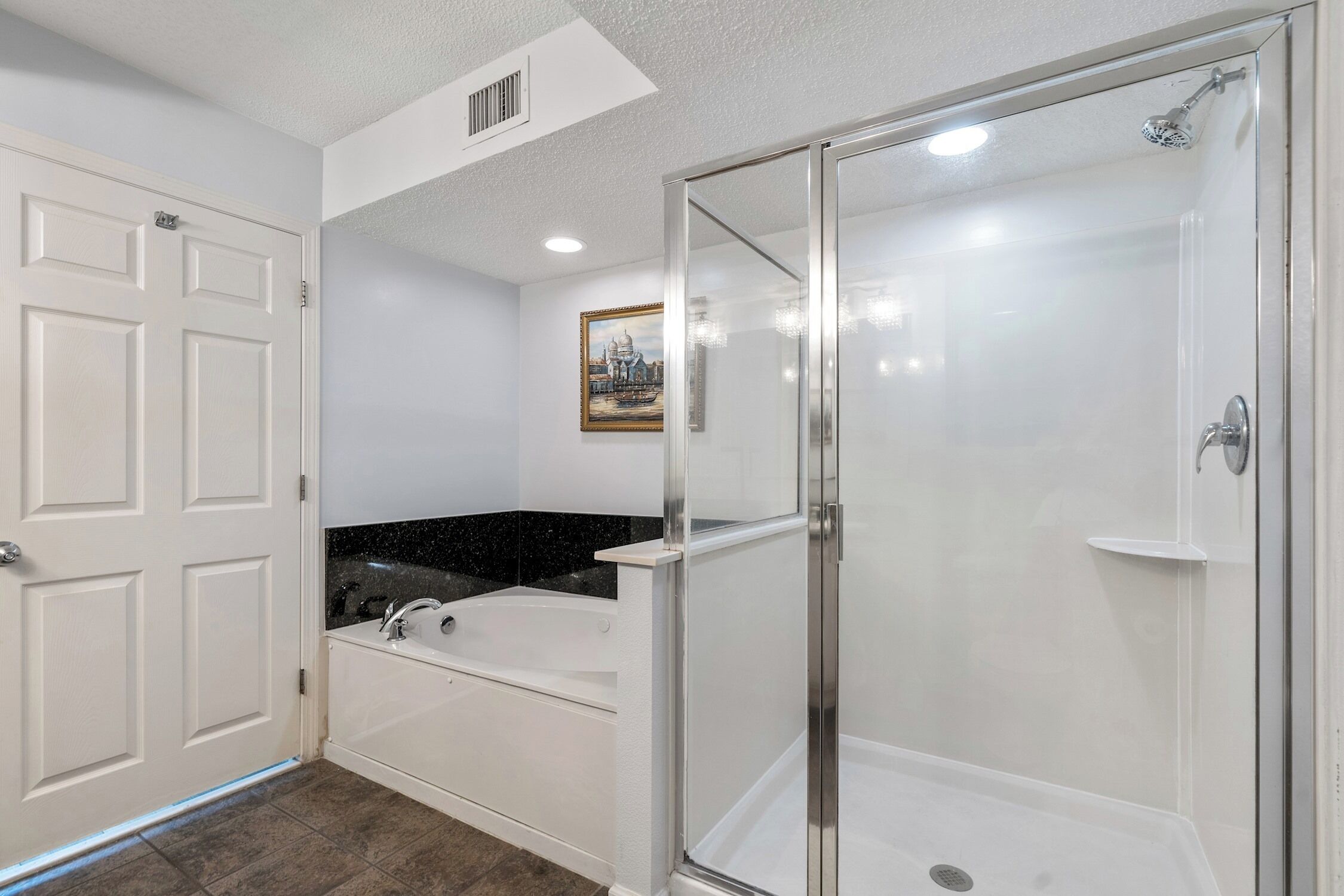 Een badkamer met een douche met glazen wand, een bad en een wastafel.