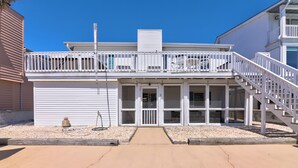 A two-story building with a balcony, a covered front porch, and a staircase leading to the upper level.