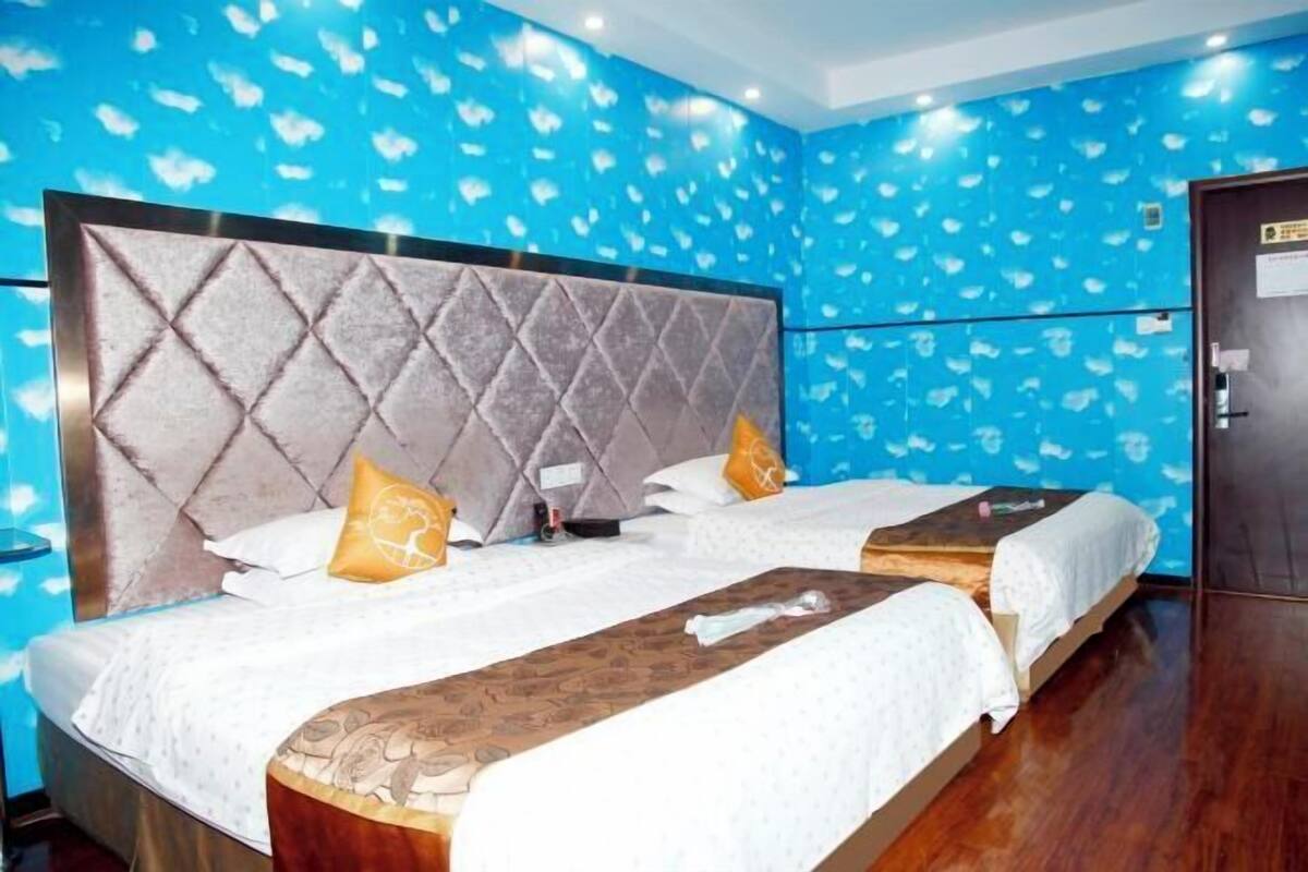A hotel room with a large bed, two bedside tables, and a wardrobe.