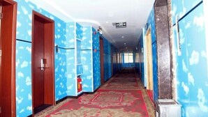 A hotel corridor with blue walls, wooden doors, and a red carpet. - Huadu Business Hotel Chenzhou (Chenzhou)