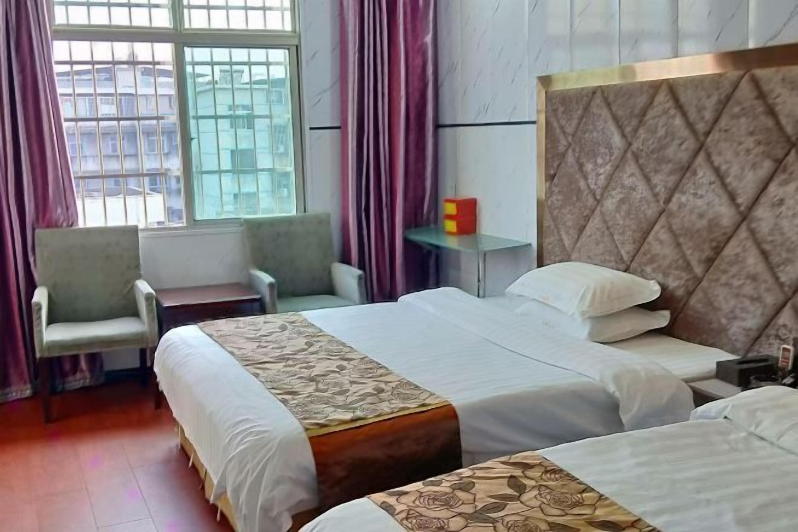 A hotel room with two beds, a desk, a chair, and a window with curtains.