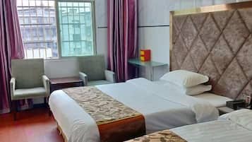A hotel room with two beds, a desk, a chair, and a window with curtains.