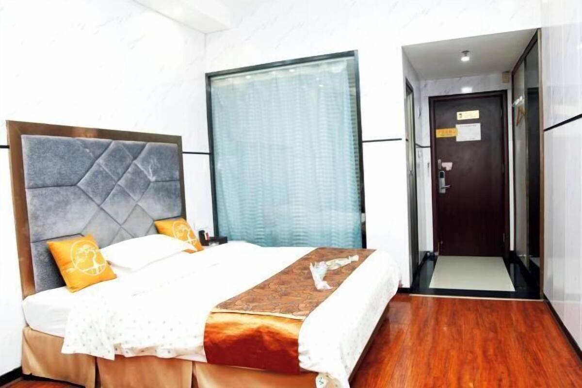 A hotel room with a bed, a window, and a door.