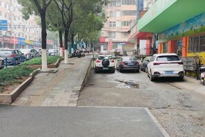 Une rue bordée de voitures garées, d’arbres et d’immeubles aux façades colorées.