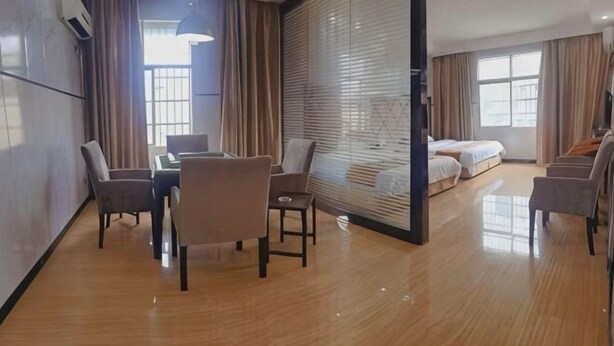 A hotel room with a wooden floor, a dining table with chairs, a sofa, a bed, and a large window with curtains. - Huadu Business Hotel Chenzhou (Chenzhou)