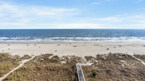 A beach with a boardwalk leading to the shore, sandy beach, and ocean.