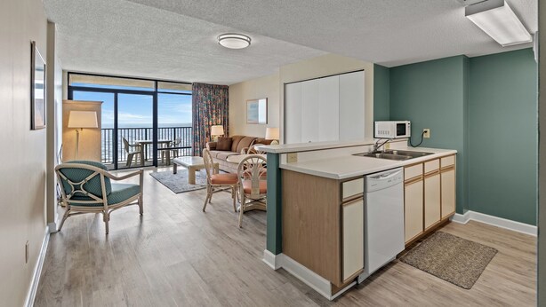 A modern apartment with a kitchen, dining area, and a balcony with a view.