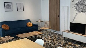 A modern living room with a sofa, coffee table, TV, and artwork on the wall. - Luma Oberkampf Apartment / Jean Pierre Timbaud (Paris)