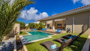 A swimming pool with lounge chairs and a patio area. - Amazing 4BR 3BA Villa Palm Beach w NEW Pool (Noord)