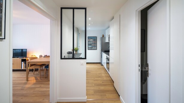 Une cuisine moderne avec des armoires blanches, un plan de travail noir et un plancher en bois.