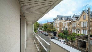 Un balcon donnant sur une rue bordée de maisons et de voitures garées.