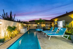 A swimming pool with lounge chairs and potted plants.