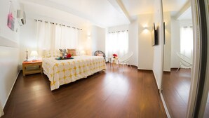Une chambre à coucher avec un lit, une table de chevet, une chaise et une petite table ornée de fleurs.