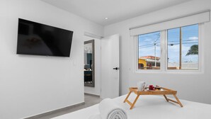 A modern hotel room with a flat-screen TV, a wooden side table with a tray, and rolled towels. - Brand NEW Private Pool King Beds Palmbeach (Noord)