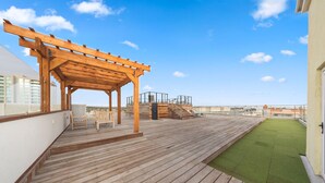 A wooden deck with a pergola, outdoor seating, and a small grassy area.