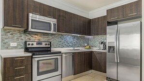 Une cuisine moderne avec des meubles en bois foncé, des appareils électroménagers en acier inoxydable et un dosseret carrelé.