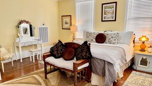 Un dormitorio con cama, mesita de noche, lámpara, cómoda, espejo y una silla.